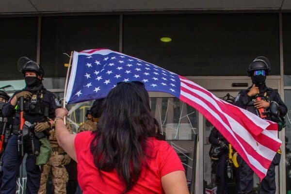 Photo: A woman agitates an American flag, while the staff of the California National Guard is outside the Federal Building during protests in response to federal immigration operations in Los Angeles, on June 10, 2025.