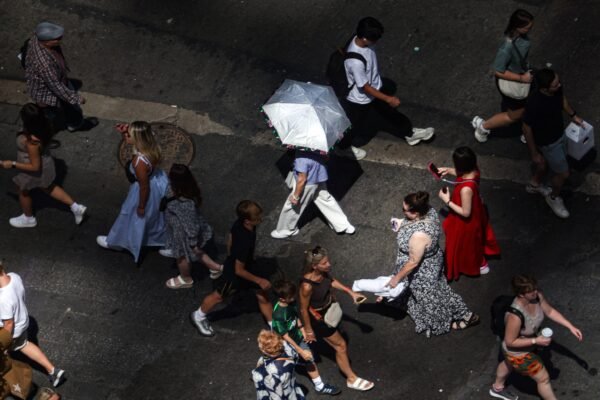 Photo: pedestrians, including a person holding an umbrella to block UV rays, walk on Times Square in New York